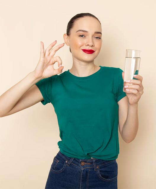 front view young female in dark green shirt and blue jeans holding glass
